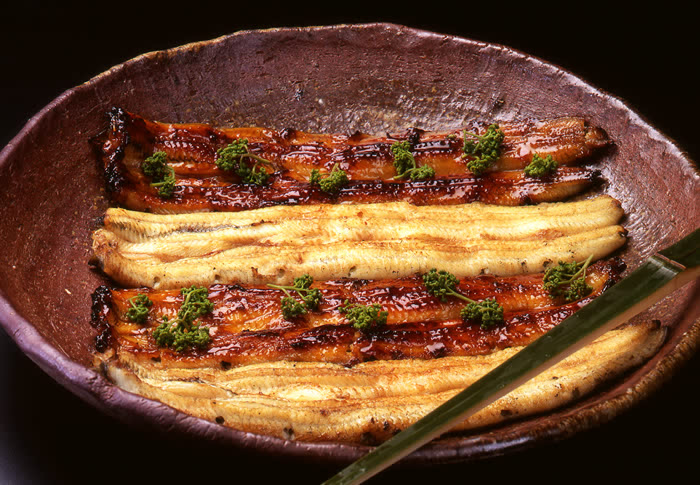 「裂き3年、串打ち7年、焼き一生」といわれている当亭名物「鰻蒲焼」。 背開きにして裂いた後、竹串にて串打ちし、一度白焼きをしてから、鰻専用の蒸し器である、いわゆる「蒸篭」にて約30分蒸し上げた後、昔ながらの「秘伝のタレ」を用いて、炭火にて丹念に焼き上げたものでございます。