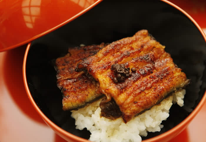 「裂き３年、串打ち７年、焼き一生」といわれている当亭名物「鰻蒲焼」。 背開きにして裂いた後、竹串にて串打ちし、一度白焼きをしてから、鰻専用の蒸し器である、いわゆる「蒸篭」にて約３０分蒸し上げた後、昔ながらの「秘伝のタレ」を用いて、炭火にて丹念に焼き上げたものでございます。